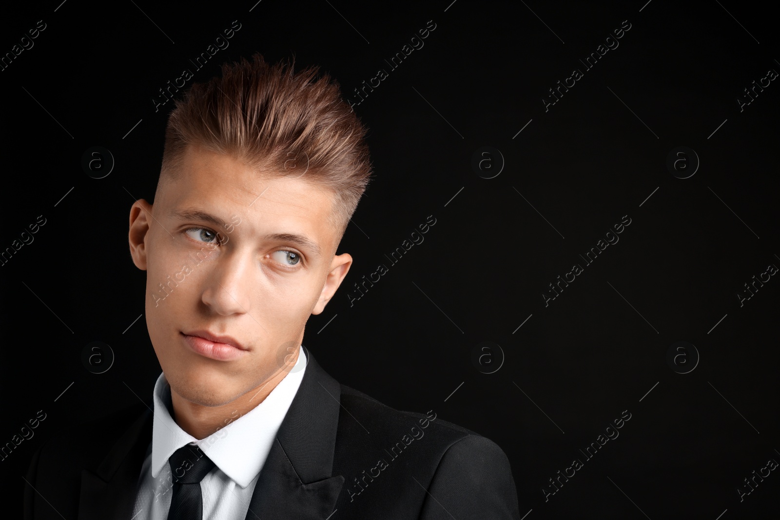 Photo of Confident young man with stylish haircut on black background. Space for text