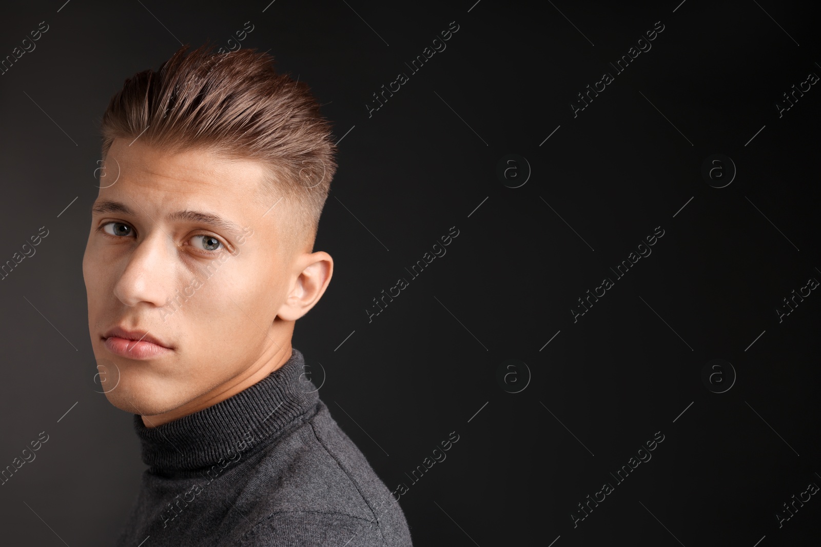 Photo of Confident young man with stylish haircut on black background. Space for text