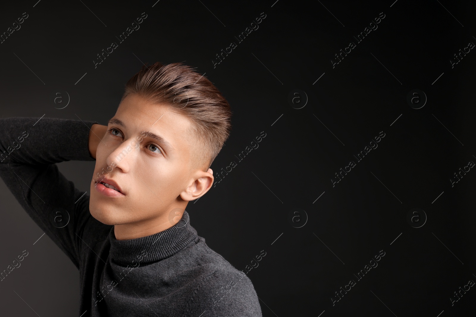 Photo of Confident young man with stylish haircut on black background. Space for text