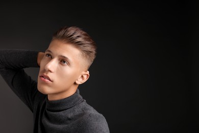 Photo of Confident young man with stylish haircut on black background. Space for text