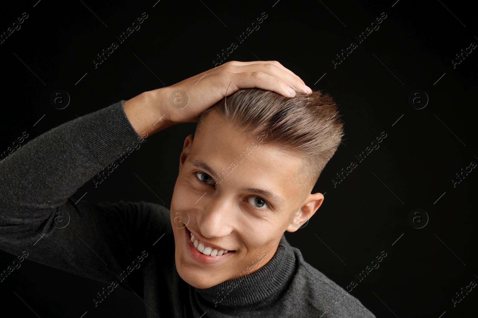 Photo of Confident young man with stylish haircut on black background