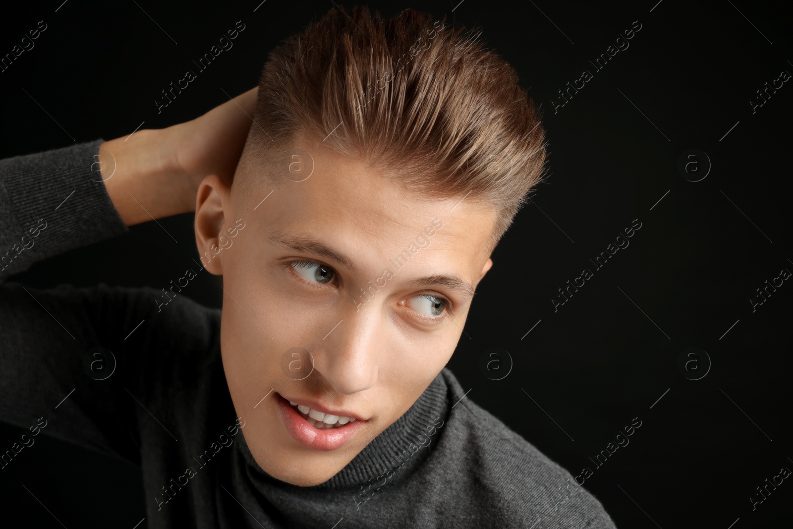 Photo of Confident young man with stylish haircut on black background