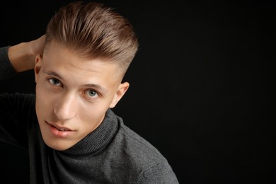 Photo of Confident young man with stylish haircut on black background. Space for text