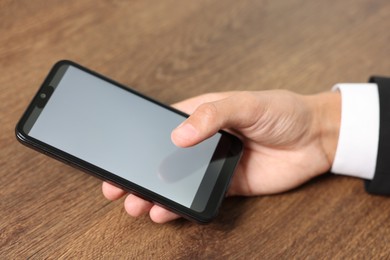 Photo of Man unlocking smartphone with fingerprint scanner at wooden table, closeup