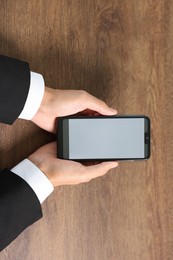 Photo of Man holding smartphone with fingerprint scanner at wooden table, closeup