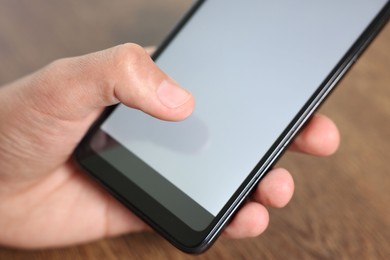 Photo of Man unlocking smartphone with fingerprint scanner at wooden table, closeup