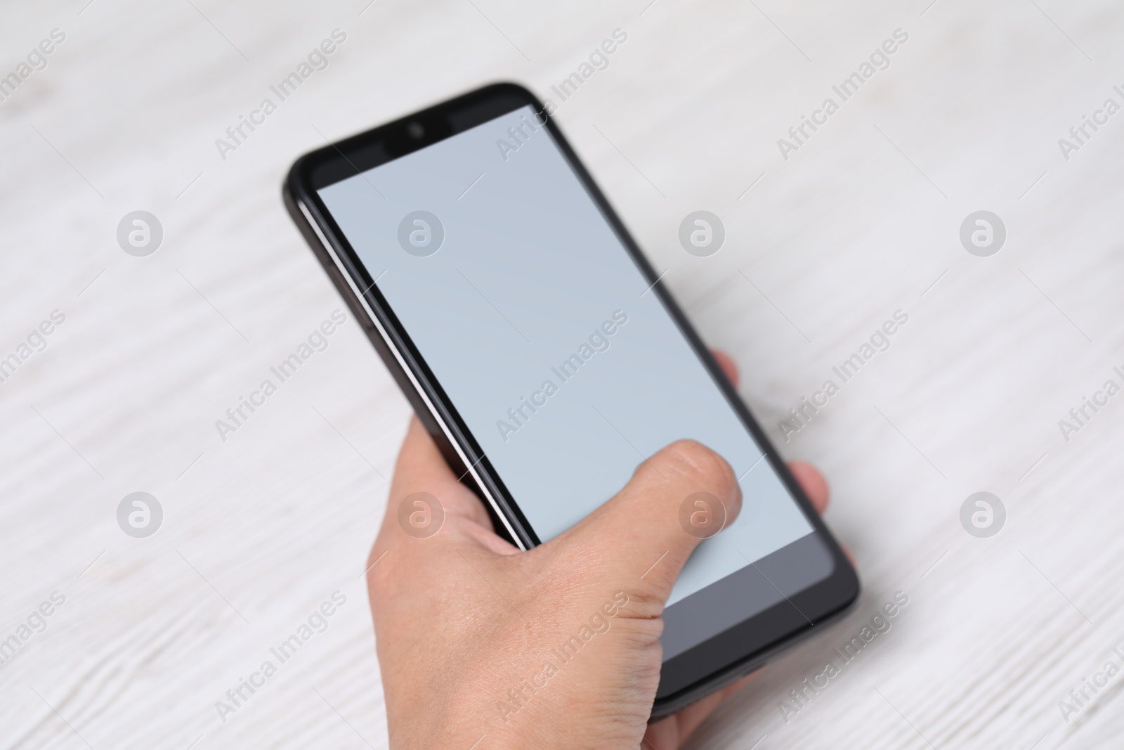 Photo of Man unlocking smartphone with fingerprint scanner at light wooden table, closeup