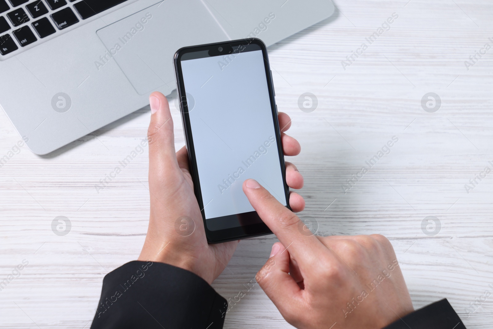 Photo of Man unlocking smartphone with fingerprint scanner at light wooden table, top view