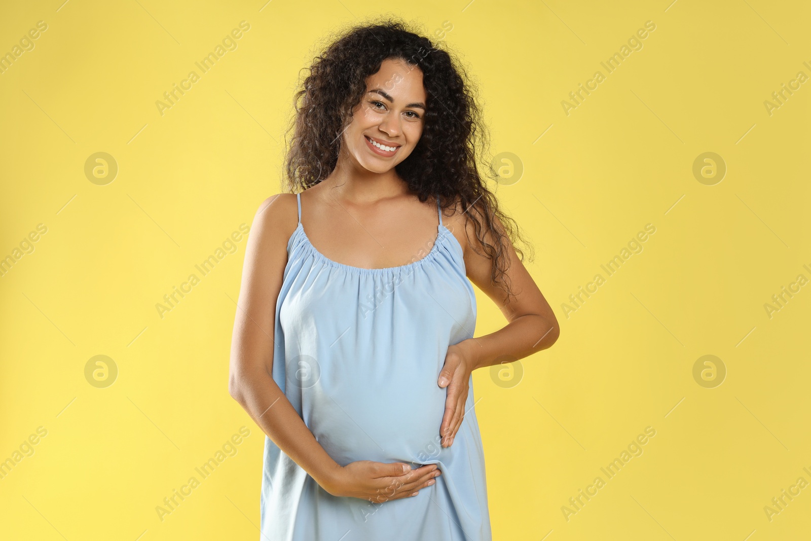 Photo of Portrait of beautiful pregnant woman on yellow background