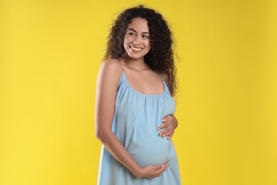 Photo of Portrait of beautiful pregnant woman on yellow background