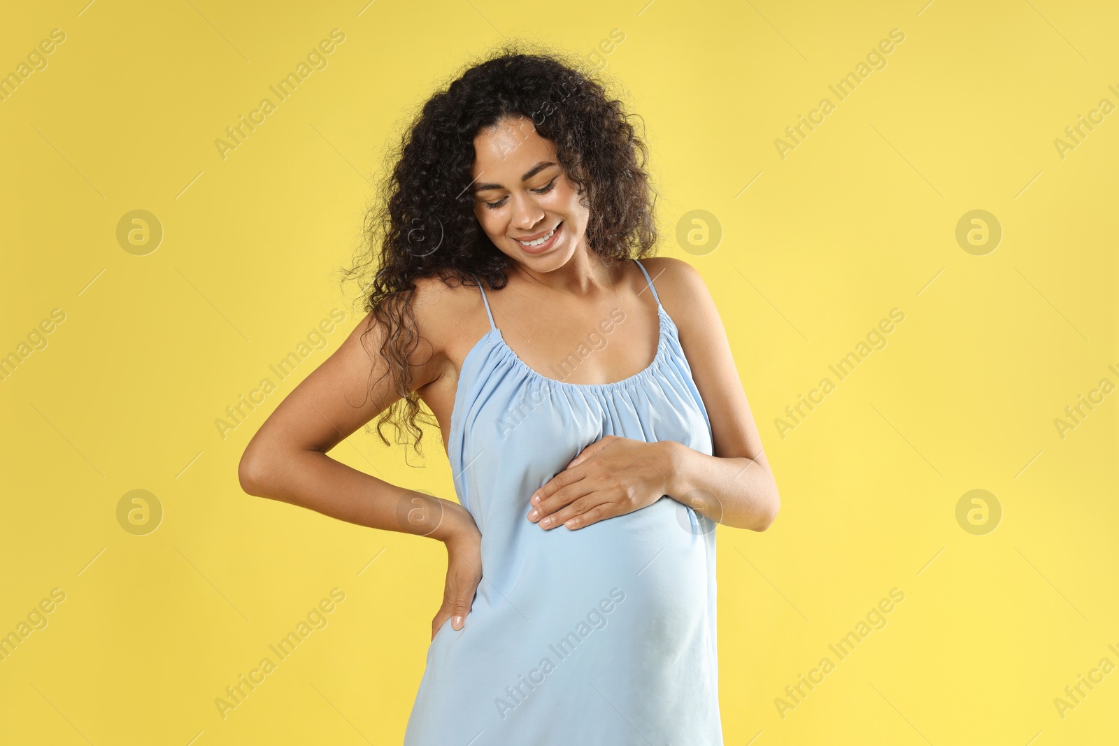 Photo of Portrait of beautiful pregnant woman on yellow background