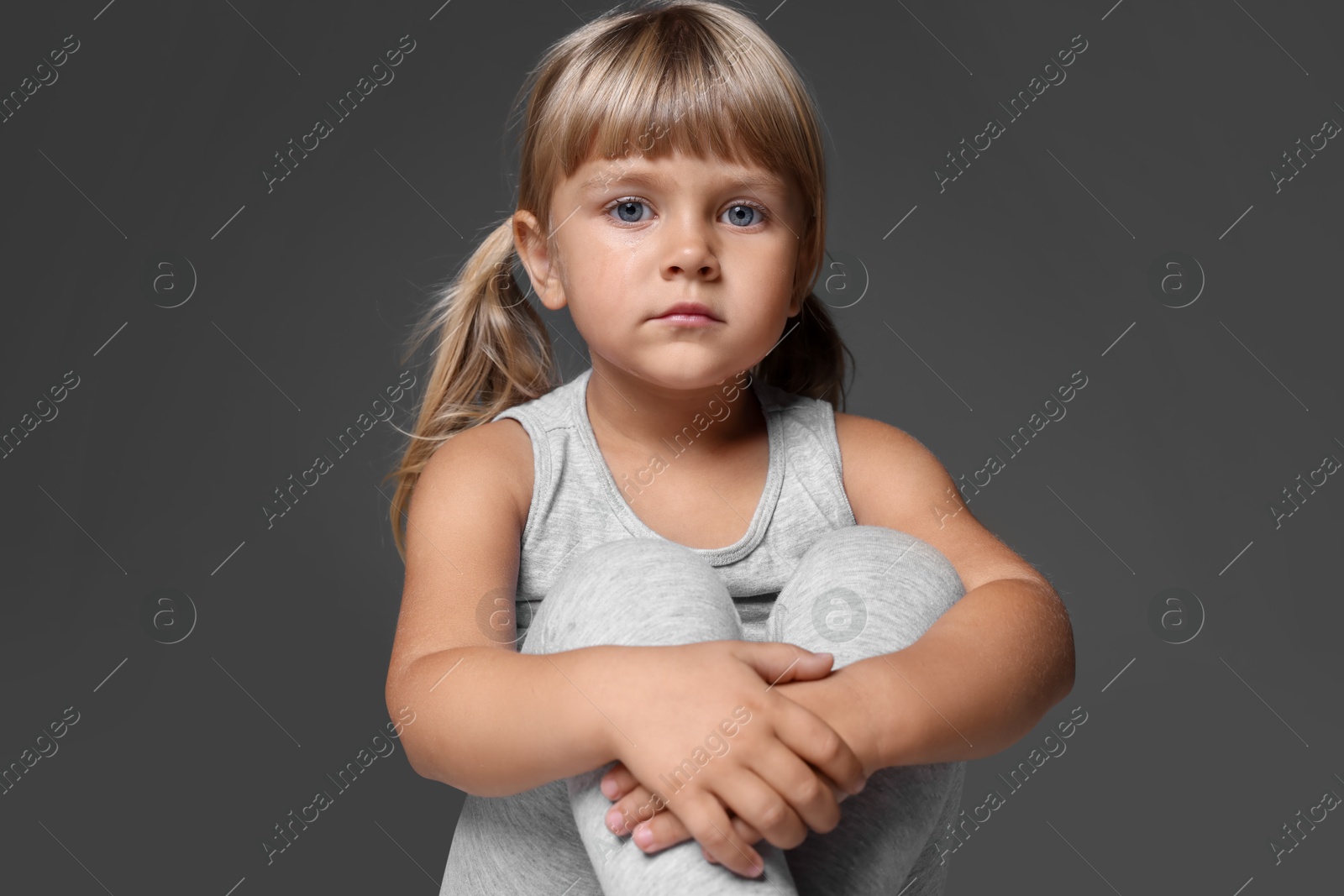 Photo of Orphanage concept. Sad little girl on grey background