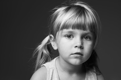 Photo of Orphanage concept. Sad little girl on dark background. Black and white effect