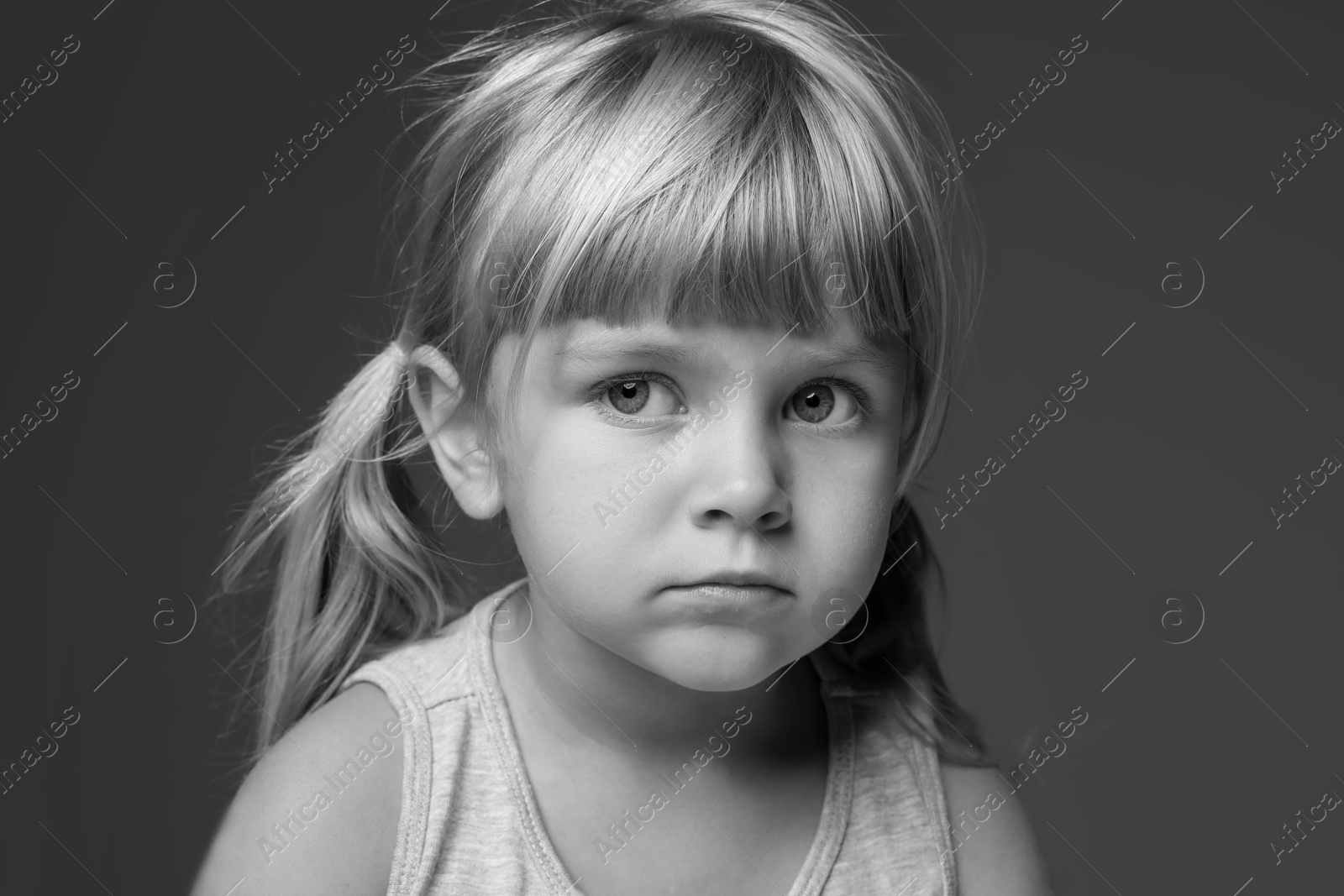 Photo of Orphanage concept. Sad little girl on dark background. Black and white effect