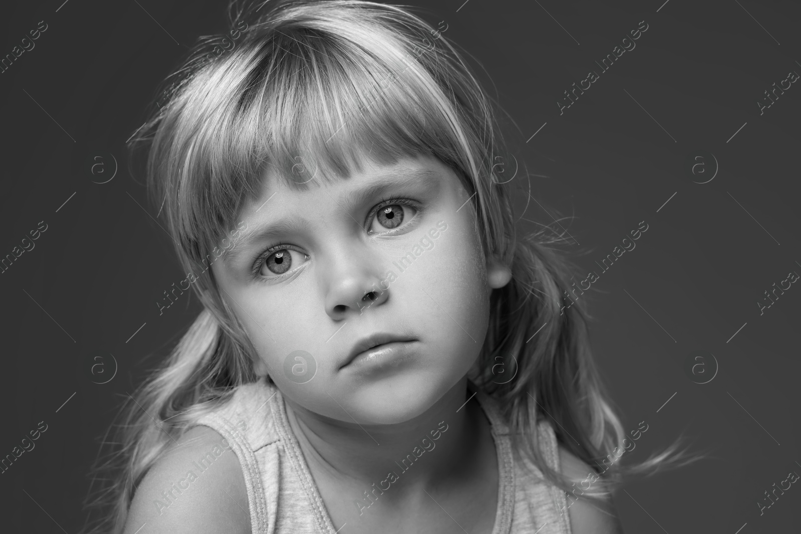 Photo of Orphanage concept. Sad little girl on dark background. Black and white effect