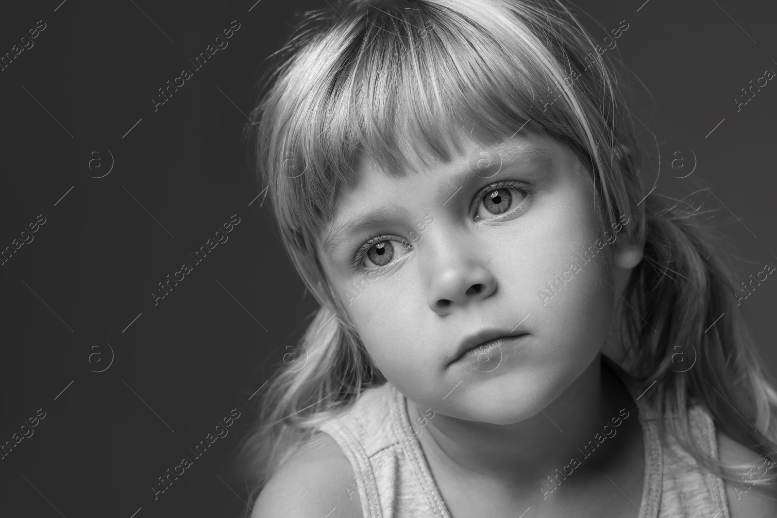 Photo of Orphanage concept. Sad little girl on dark background. Black and white effect