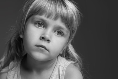 Photo of Orphanage concept. Sad little girl on dark background. Black and white effect