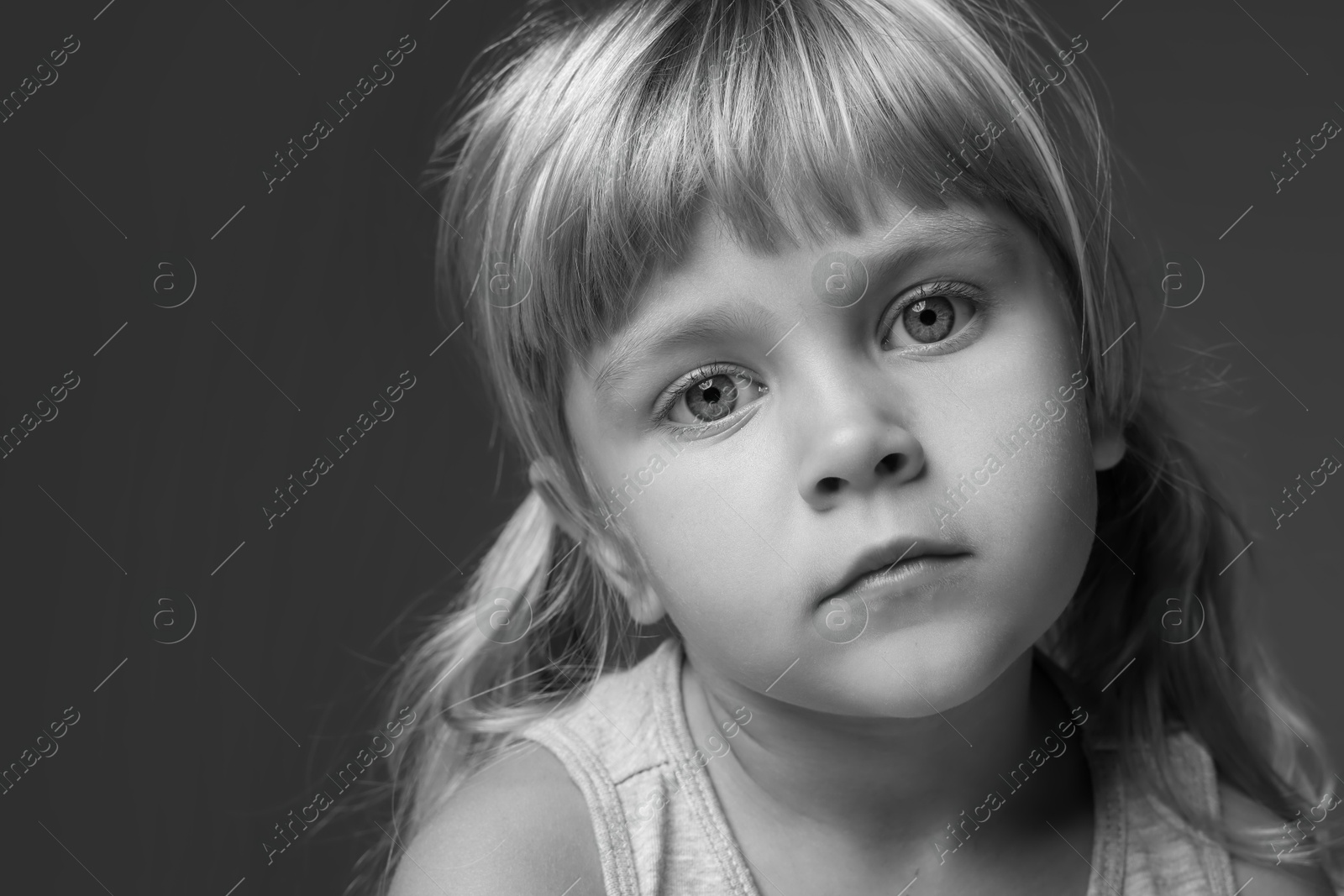 Photo of Orphanage concept. Sad little girl on dark background. Black and white effect