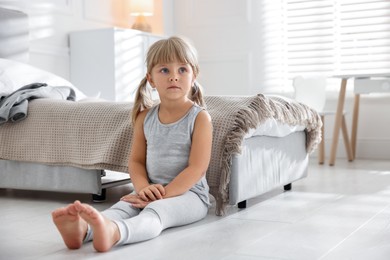 Photo of Orphanage concept. Sad little girl on floor in child`s room