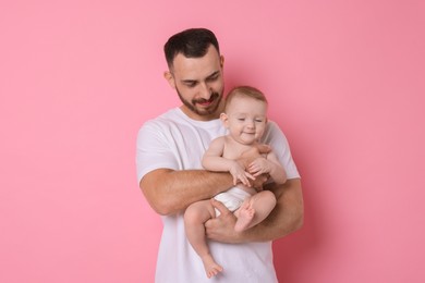 Father with his cute baby on pink background