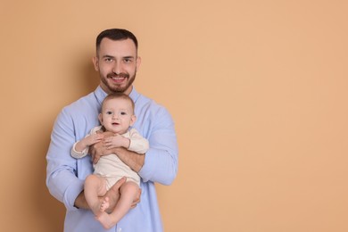 Photo of Father with his cute baby on beige background, space for text