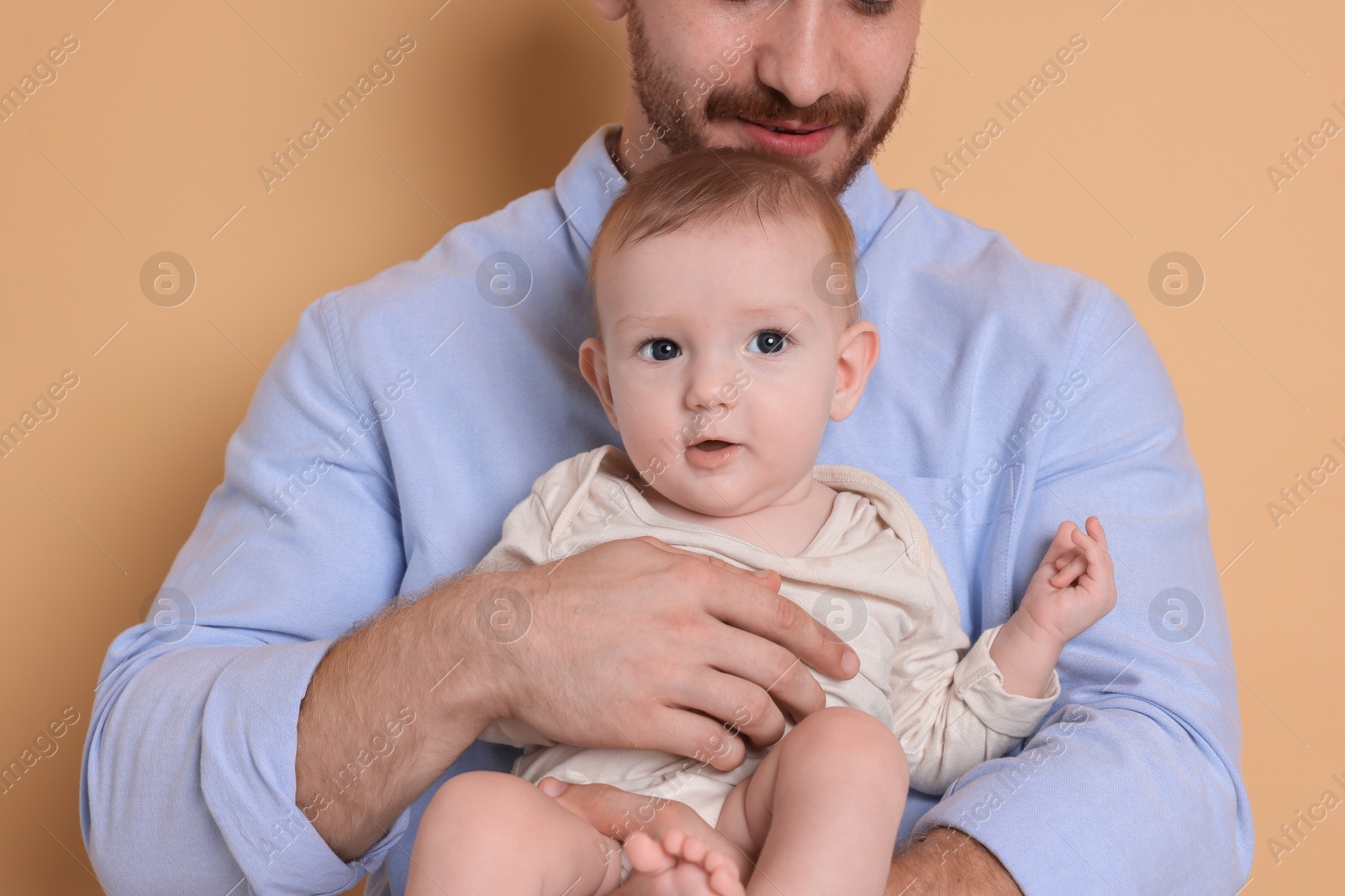 Photo of Father with his cute baby on beige background