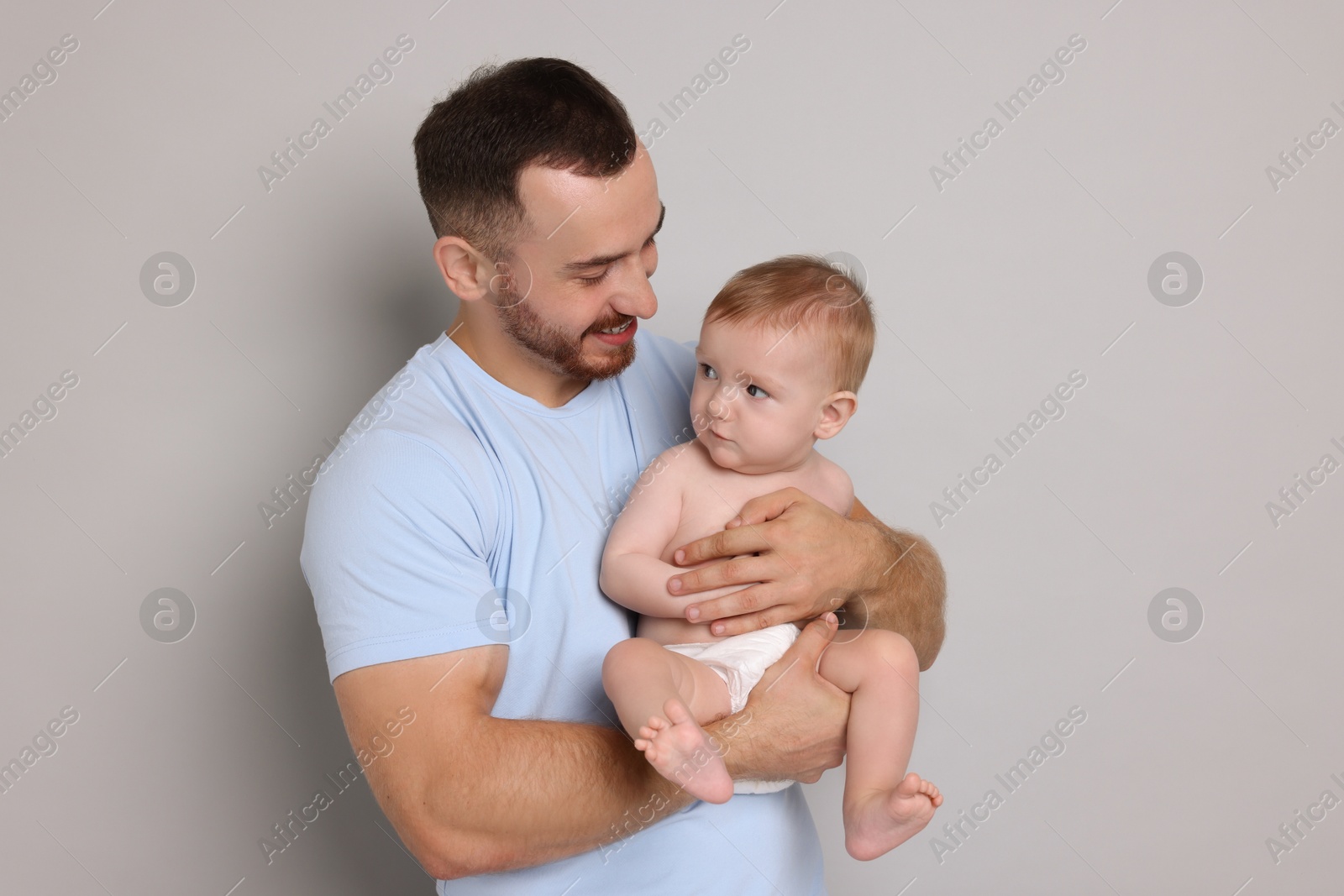 Photo of Father with his cute baby on grey background