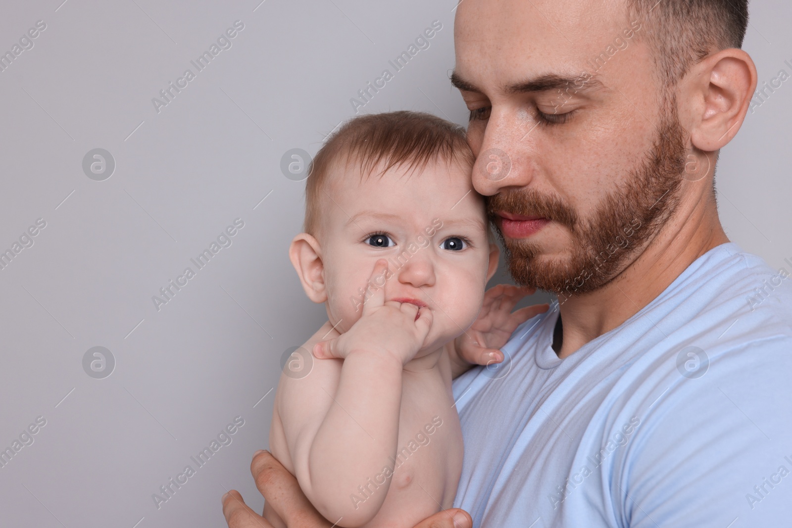 Photo of Father with his cute baby on grey background, closeup. Space for text