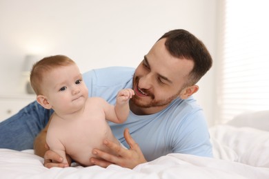 Photo of Father with his cute baby on bed at home