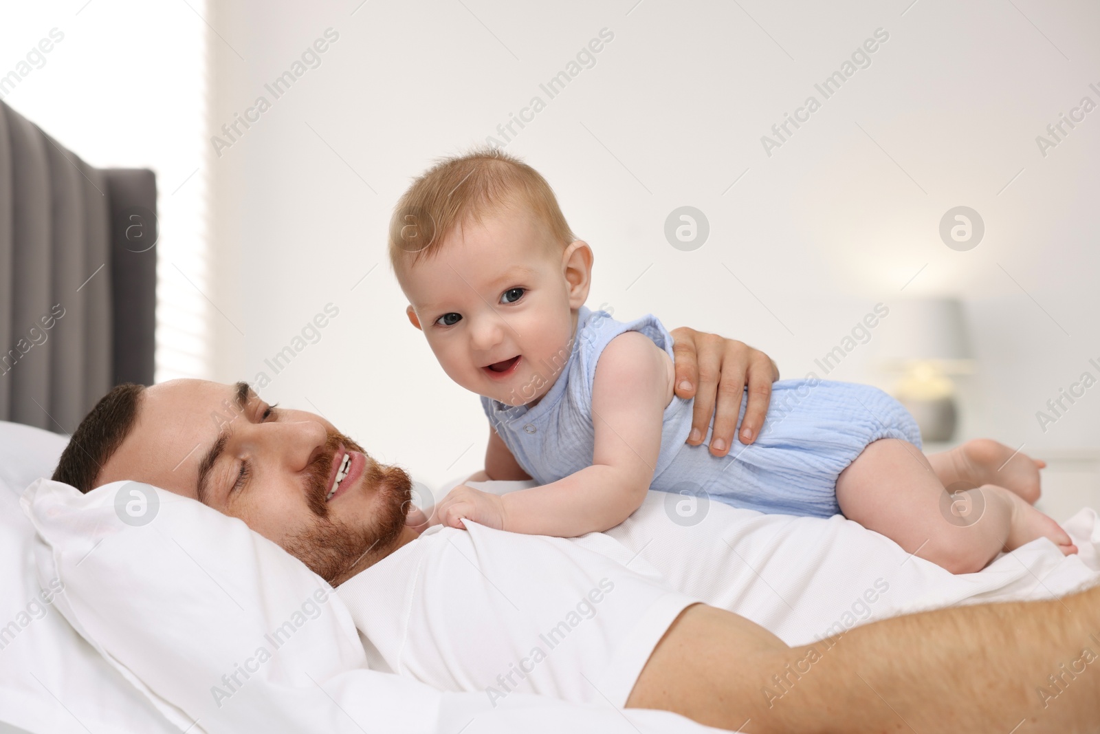 Photo of Father with his cute baby on bed at home