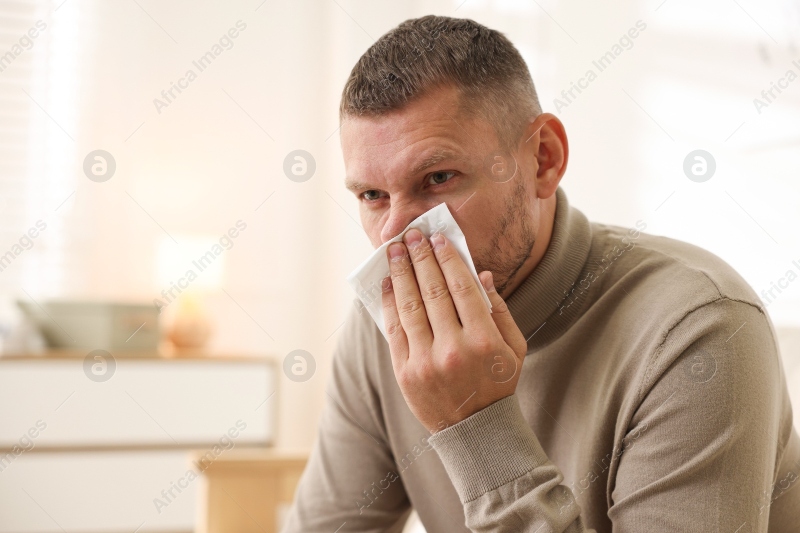 Photo of Man with tissue blowing runny nose at home. Space for text