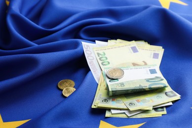 Photo of Euro banknotes and coins on European Union flag, closeup