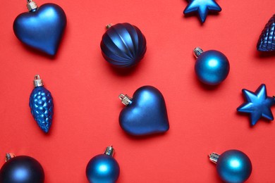 Photo of Blue Christmas baubles on red background, flat lay