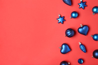 Photo of Blue Christmas baubles on red background, flat lay. Space for text