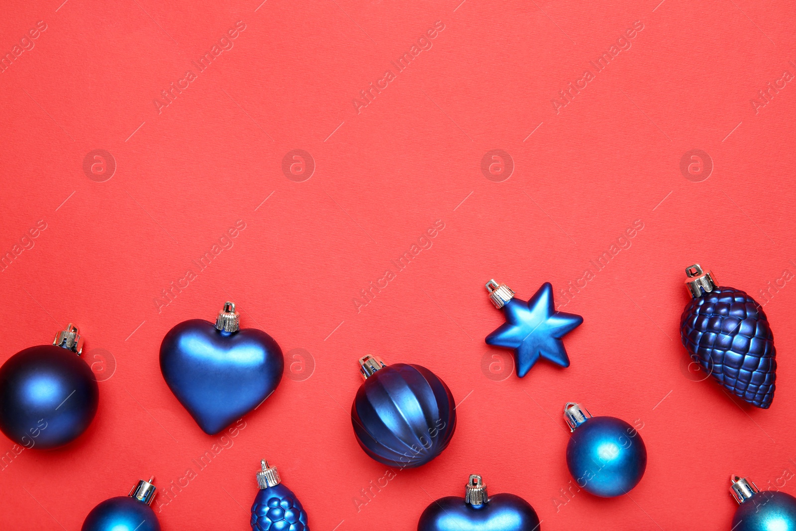 Photo of Blue Christmas baubles on red background, flat lay. Space for text