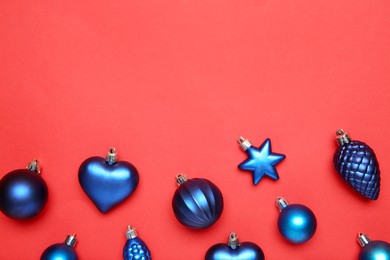 Photo of Blue Christmas baubles on red background, flat lay. Space for text