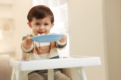 Photo of Cute little baby eating healthy food in high chair at home