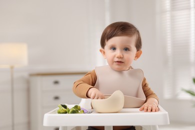 Photo of Cute little baby eating healthy food from bowl in high chair at home, space for text