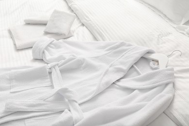 Photo of Bed with clean linens, towels and bathrobe indoors, closeup