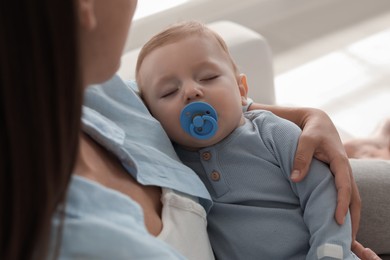 Photo of Mother with her sleeping baby on sofa indoors, closeup