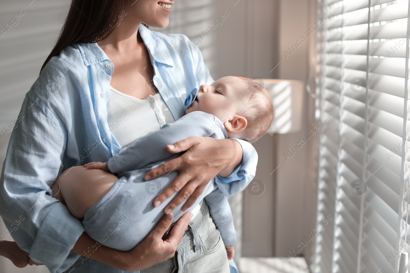 Photo of Mother holding her sleeping baby at home, closeup