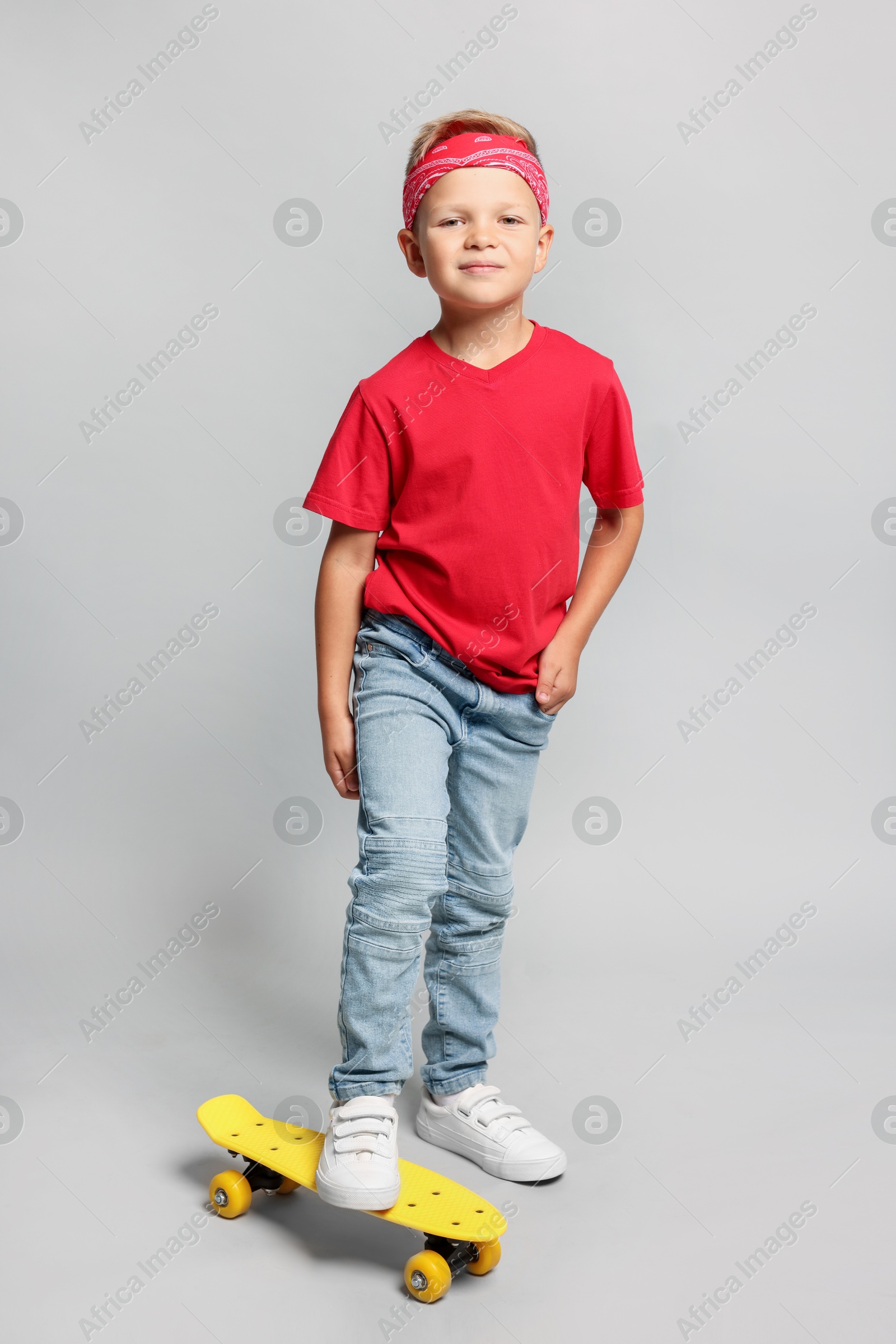 Photo of Little boy with skateboard on light grey background