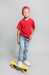 Little boy with skateboard on light grey background