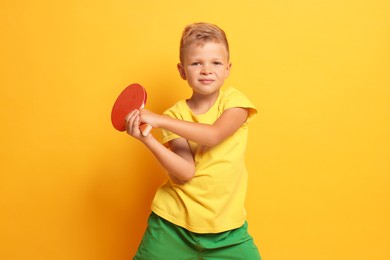 Little boy with ping pong racket on orange background