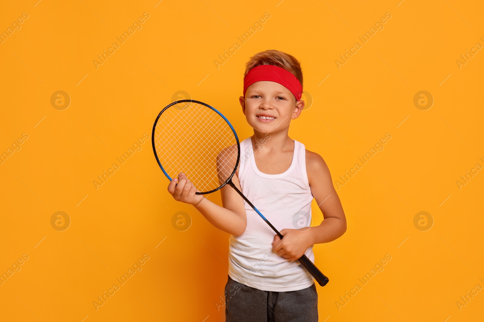 Photo of Little boy with badminton racket on orange background