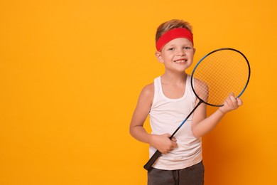 Photo of Little boy with badminton racket on orange background, space for text