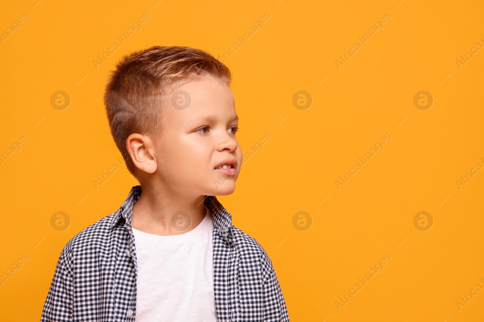 Photo of Portrait of little boy with stylish clothes on orange background, space for text