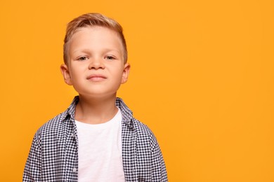 Photo of Portrait of little boy with stylish clothes on orange background, space for text