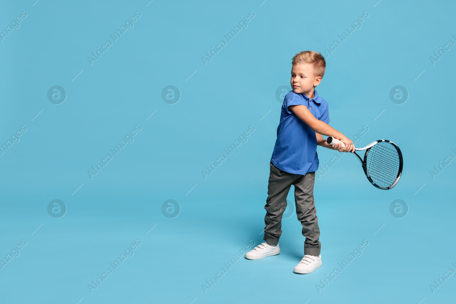 Photo of Little boy with tennis racket on light blue background