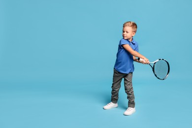 Little boy with tennis racket on light blue background